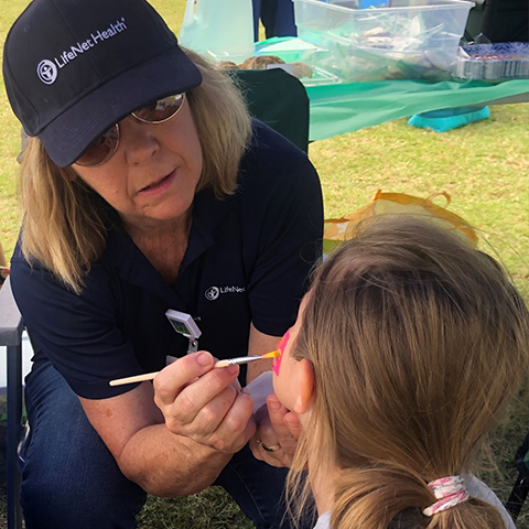A LifeNet Health volunteer painting a girl's face